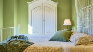 Une chambre à coucher comprenant un lit, une armoire blanche, une table de chevet avec une lampe et une tête de lit décorative en métal.