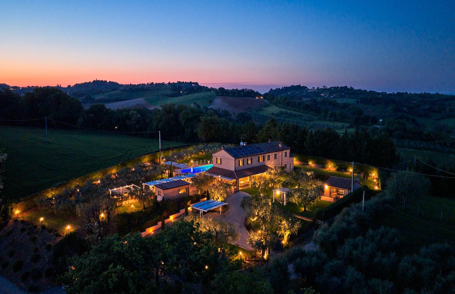 A large estate with multiple buildings, a swimming pool, and well-lit outdoor areas.