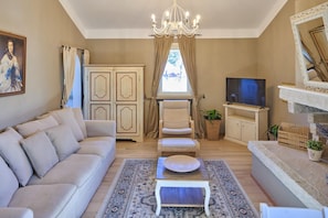 A living room with a sofa, armchair, TV, and decorative items.