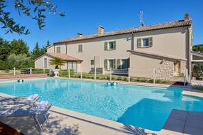 A swimming pool with lounge chairs and a stone wall.