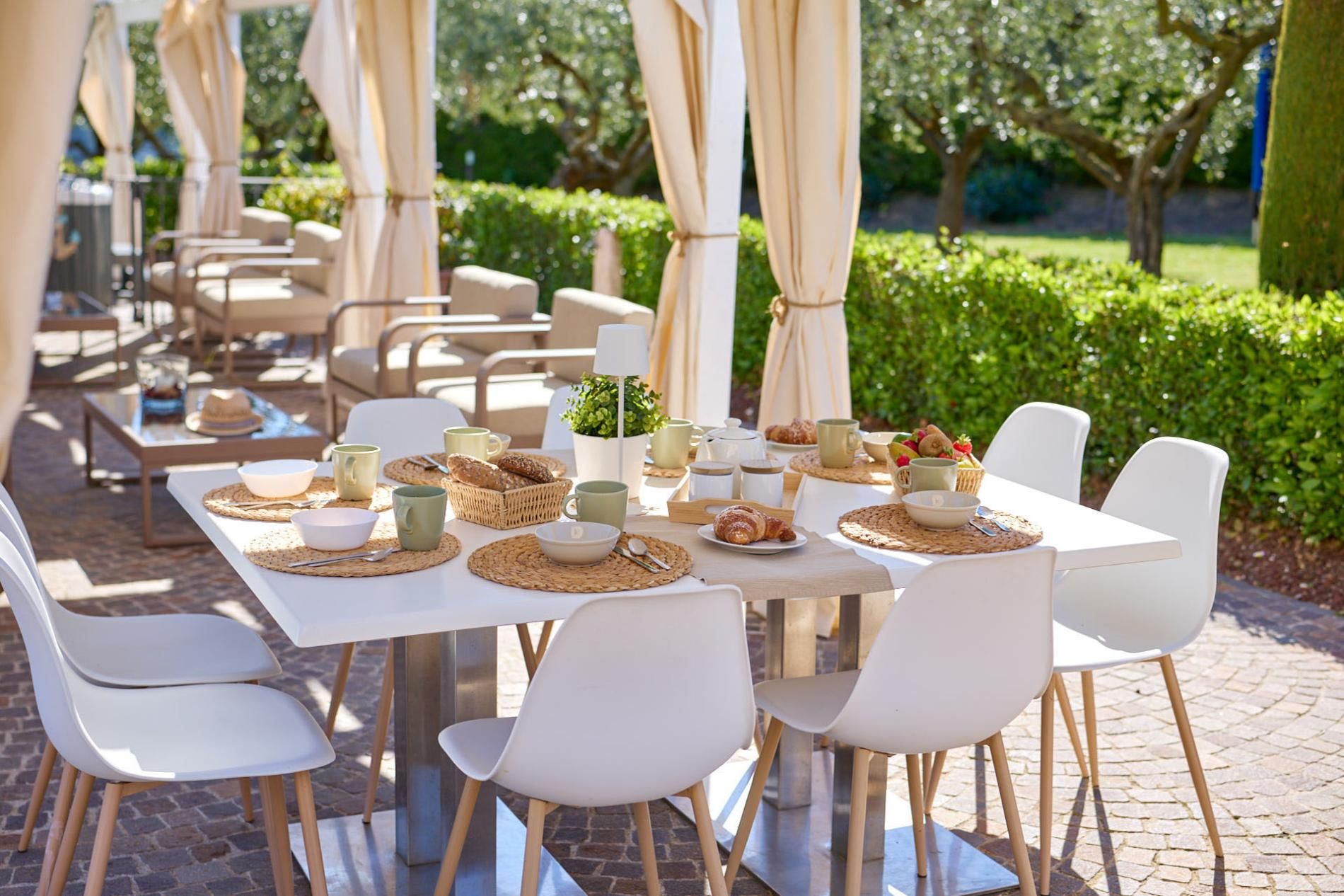 Un espace de restauration en plein air avec des tables et des chaises blanches, disposées en rangée.