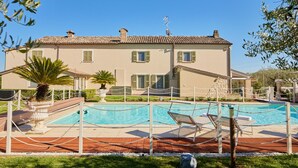 Un bâtiment à deux étages doté d’une piscine et de chaises longues.