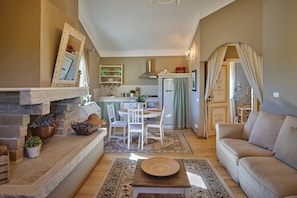 Ein gemütliches Wohnzimmer mit Kamin, eine Essecke mit Tisch und Stühlen sowie eine Küche im Hintergrund.
