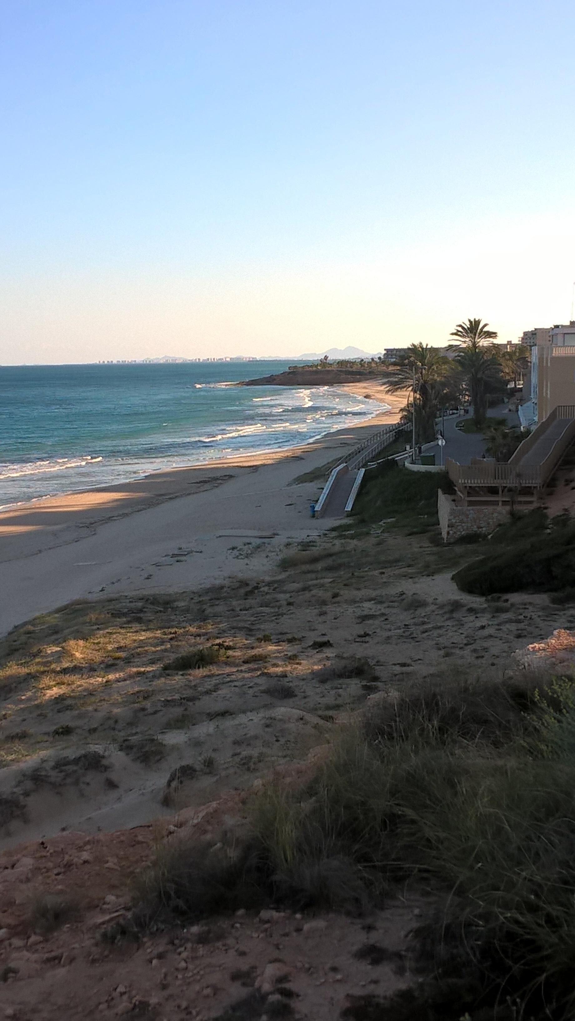Una playa con un sendero que conduce a un edificio con balcón.
