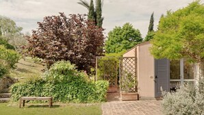 A garden with a bench, a pergola, and a building with a window. - VILLA GLICINI: A romantic countryside cottage with a pool (Ostra)