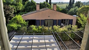 A house with a sloped roof, surrounded by greenery and trees. - VILLA GLICINI: A romantic countryside cottage with a pool (Ostra)