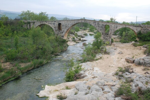 A stone bridge over a river with surrounding greenery and a hilly landscape in the background. - Roussillon Gargas: Mansion - Roussillon (Gargas)