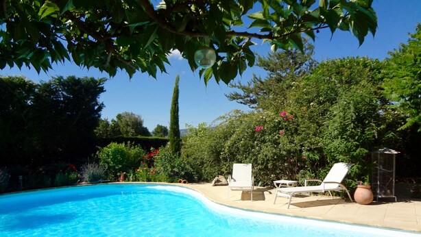 A swimming pool with two lounge chairs and a table, surrounded by lush greenery and a clear blue sky. - Roussillon Gargas: Mansion - Roussillon (Gargas)