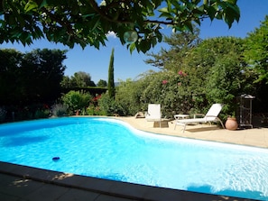 A swimming pool with two lounge chairs and a table, surrounded by lush greenery and a clear blue sky. - Roussillon Gargas: Mansion - Roussillon (Gargas)