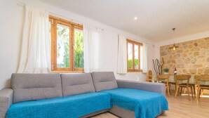 Ein modernes Wohnzimmer mit einer grauen Eckcouch, einem Esstisch mit Stühlen und einer Steinwand.