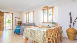 A spacious living area with a dining table, chairs, a sofa, and a large window.