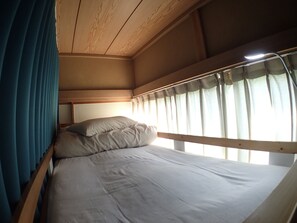 A bunk bed with a headboard, a window with curtains, and a bedside lamp. - Guesthouse SORA - Hostel (Minamiizu)
