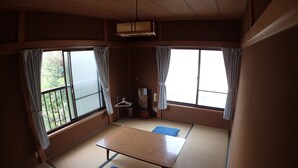 A traditional Japanese room with tatami flooring, a low table, and two cushions. - Guesthouse SORA - Hostel (Minamiizu)