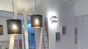 A modern kitchen with a wooden table, bar stools, pendant lights, and a 'HELLO' sign on the wall. - ROMANTIC and light apartment in Oportodowntown with mezzanine. (Porto)