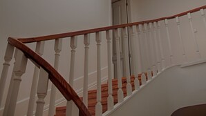 A staircase with white balusters and a wooden handrail leading to a room with a skylight. - ROMANTIC and light apartment in Oportodowntown with mezzanine. (Porto)