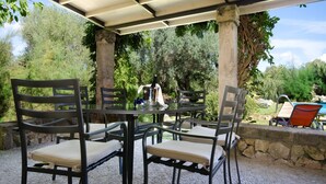 An outdoor patio with a round table and four chairs, surrounded by greenery and a stone wall. - LA TORRE  Ref. VP86 (Pollensa / Pollença)