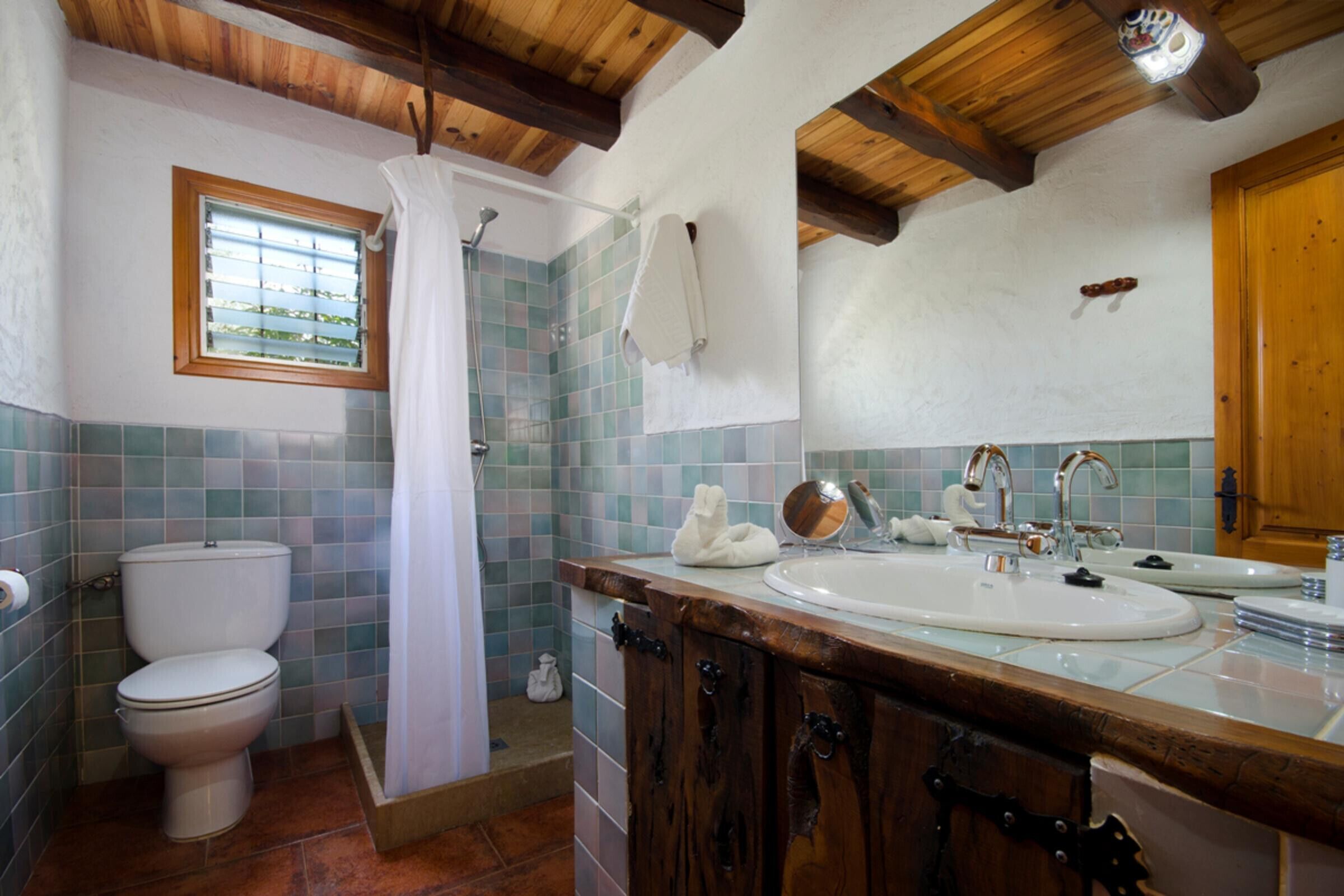 A bathroom with a toilet, shower, and sink.
