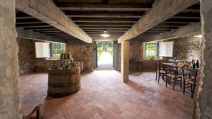 Une cave rustique avec des poutres apparentes, un tonneau et un coin repas comprenant une table et des chaises.