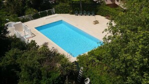 An aerial view of a rectangular swimming pool surrounded by lush greenery, with a few lounge chairs and a small seating area. - Antibes - attractive apartment with panoramic views & 300m from 2 beaches (Antibes)