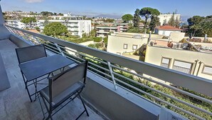 A balcony with a table and chairs, overlooking a residential area with buildings and trees. - Antibes - attractive apartment with panoramic views & 300m from 2 beaches (Antibes)