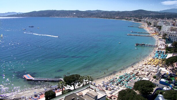 A coastal beach with clear waters, a pier, and beach umbrellas. - Antibes - attractive apartment with panoramic views & 300m from 2 beaches (Antibes)