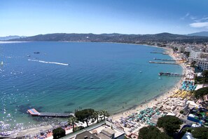 A coastal beach with clear waters, a pier, and beach umbrellas.