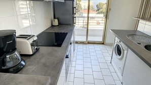 A modern kitchen with a built-in washing machine, a coffee maker, and a toaster. - Antibes - attractive apartment with panoramic views & 300m from 2 beaches (Antibes)