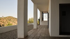 A corridor with white columns, a tiled floor, and a view of a hilly landscape. - Piltraque - our holiday country villa to rent in the Spanish Coutryside (Riogordo)