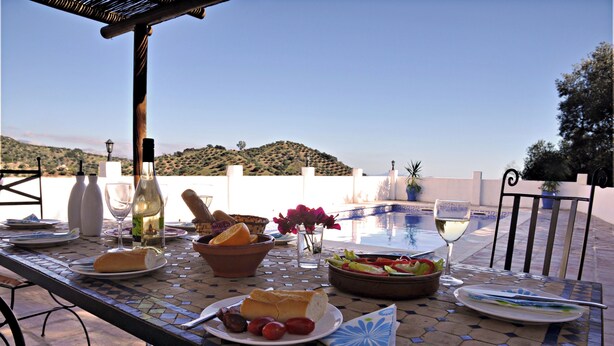 A dining table set outdoors with food, drinks, and a view of a hill. - Piltraque - our holiday country villa to rent in the Spanish Coutryside (Riogordo)