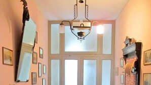 Un couloir doté d’un sol à carreaux, d’un piano à queue, d’un miroir et d’un lustre.