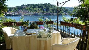 Une table dressée pour deux personnes, avec vue sur un lac et des bâtiments en arrière-plan.