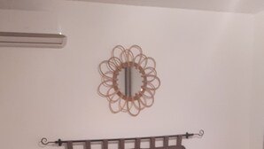 Quarto com cama, duas mesas de cabeceira, luminária, espelho decorativo e tapete marrom.