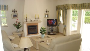 A living room with a fireplace, sofa, coffee table, and television. - Beautiful 4 bedroom villa in the Alto Golf (ALVOR)