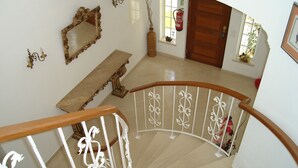 A staircase with a wooden handrail and white balusters, leading to a landing with a bench and a mirror. - Beautiful 4 bedroom villa in the Alto Golf (ALVOR)