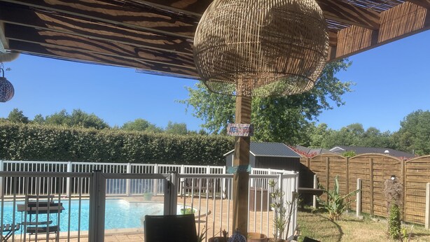 A covered patio area with a pool, outdoor furniture, and a fenced backyard.