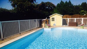 A clear swimming pool with a wooden deck and a fenced area.