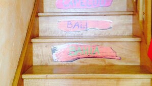 A wooden staircase with hand-painted signs indicating different destinations.