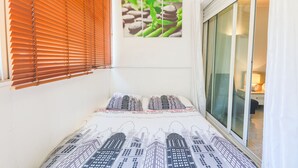 Un dormitorio con cama, ventana con persianas y un cuadro en la pared.