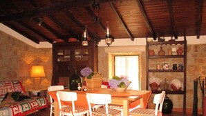 Un coin repas avec une table en bois, des chaises blanches, une lampe et un vase rempli de fleurs.