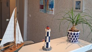 Una habitación con una encimera blanca, un velero modelo, un faro y una planta en maceta.