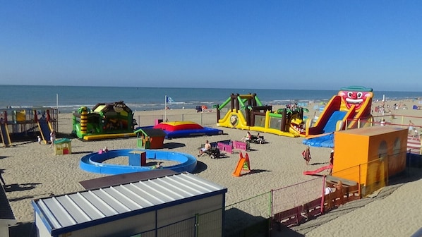 Ein Strand mit aufblasbaren Spielgeräten und einem eingezäunten Bereich.