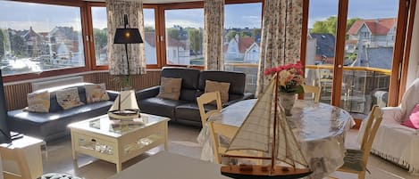 A spacious living room with a sofa, a coffee table, and a dining table with a sailboat model.