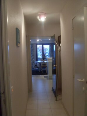 A narrow hallway with a door on the right and a window at the end. - Apartment/ flat - (Coxyde)