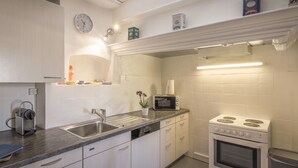 A modern kitchen with white cabinets, a stainless steel sink, a microwave, and a stove.