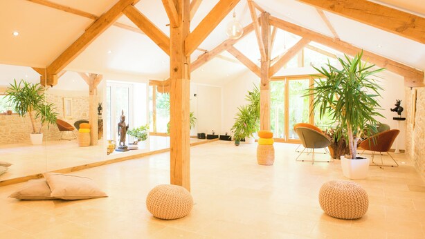 Un intérieur spacieux avec de hauts plafonds, des poutres en bois et de nombreuses plantes en pot.