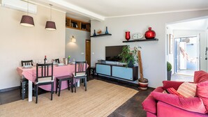 Un coin repas avec une table dressée pour quatre personnes, un canapé et un meuble pour la télévision.