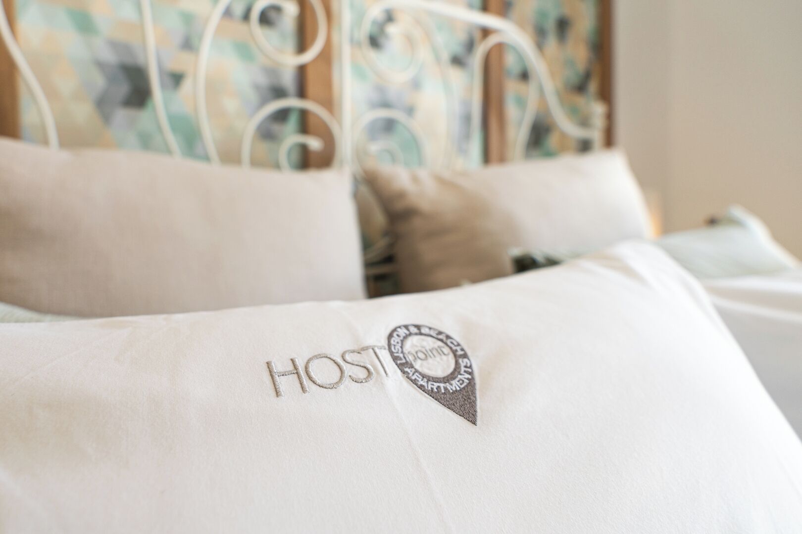 A bed with a pillow featuring the word "HOST" and a logo.
