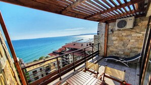 A balcony with a view of the sea, stone walls, and a ceiling fan. - Luxury Penthouse Apartment with Panoramic Sea Views (Sveti Vlas)