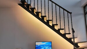 A modern staircase with a glass railing, a flat-screen TV on a black entertainment unit, and a minimalist design. - Luxury Penthouse Apartment with Panoramic Sea Views (Sveti Vlas)
