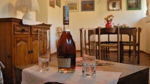 En flaskelikør på et bord med to glas, en lampe og et træskab i et rum med billeder i rammer på væggen.